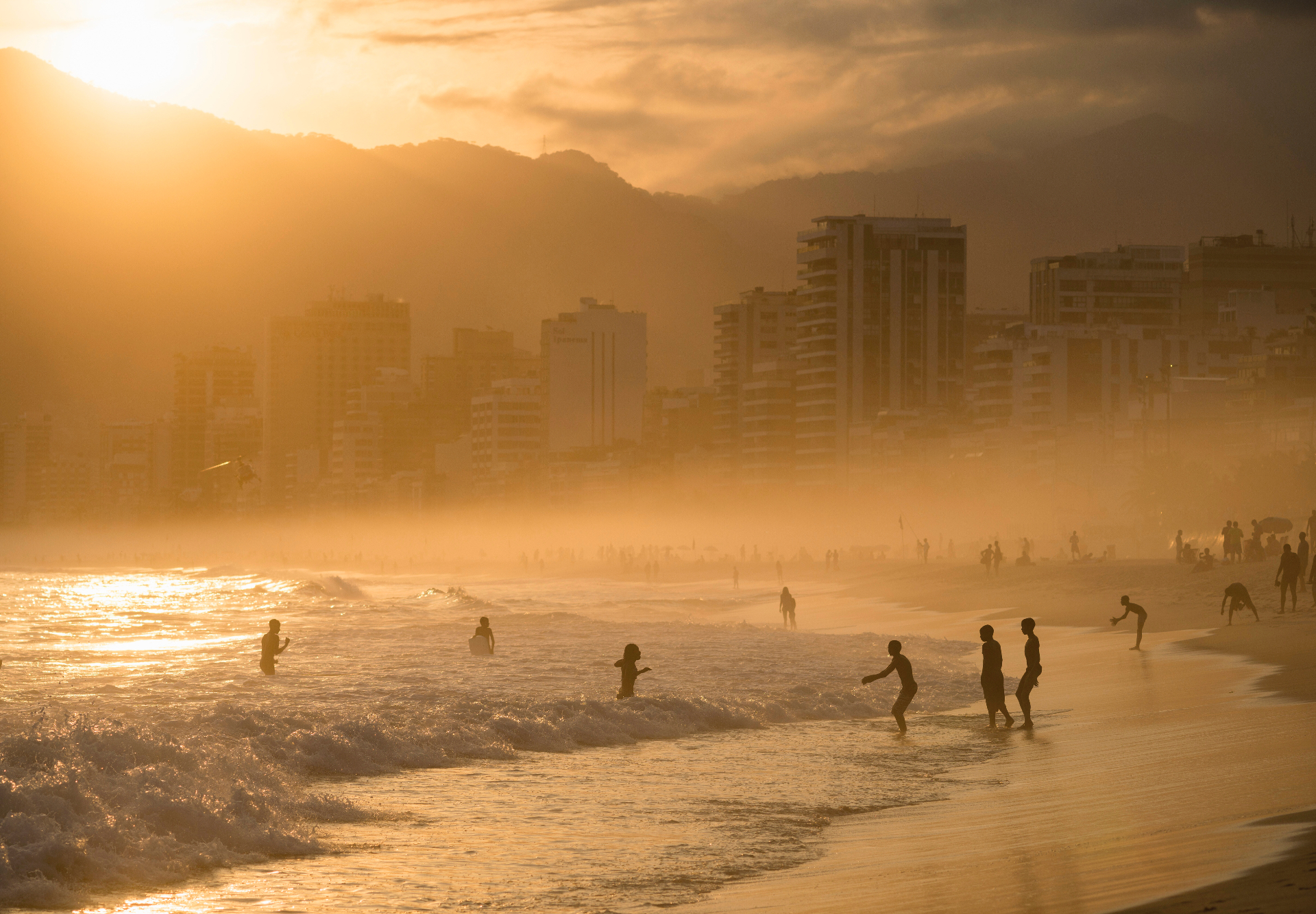 Golden hour at Ipanema beach with the Rio skyline in the mist